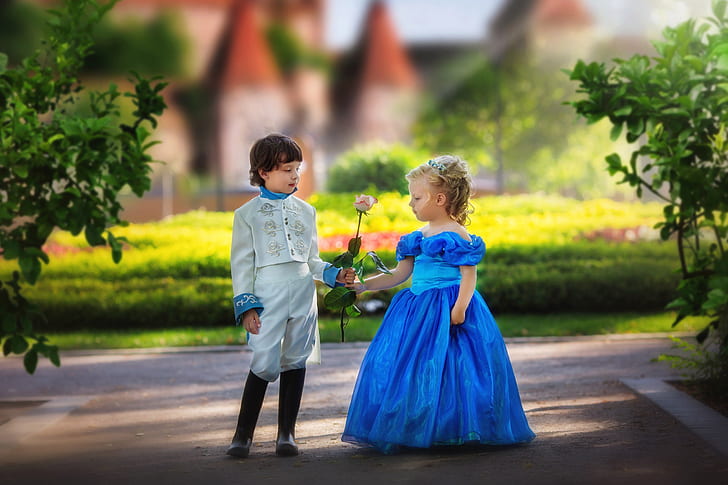 boy in white suit giving flower to a girl in blue gown