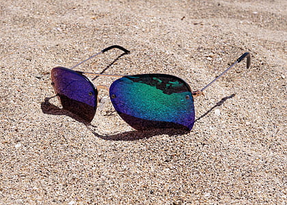photo of green flash tinted aviator-style sunglasses on sand