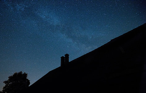 silhouette of house and tree under starry night