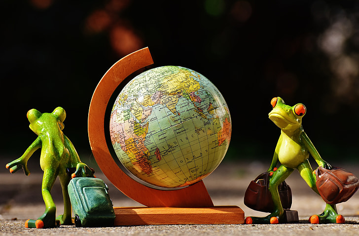 two green frogs holding luggage bags table figure
