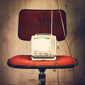 white CRT television on red chair
