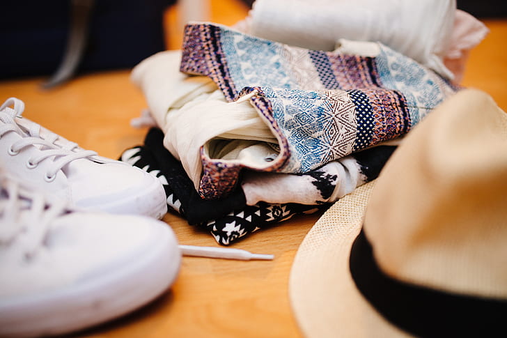 closeup photo of shoes, clothes, and hat on wooden surface