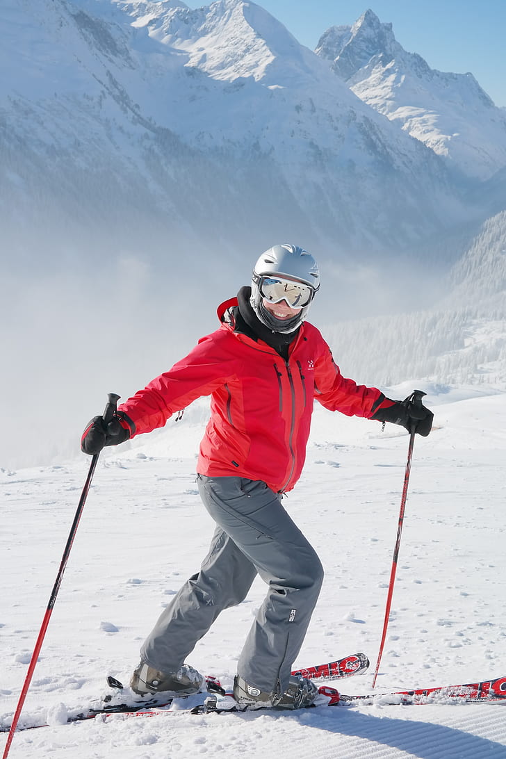 man wearing red zip-up jacket and gray pants with skiblades on snow