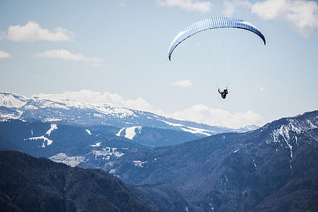 birds eye photography of person with parachute floating above mountains