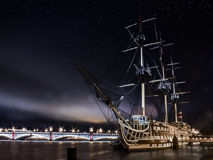 galleon ship sailing on body of water near bridge under stars nighttime
