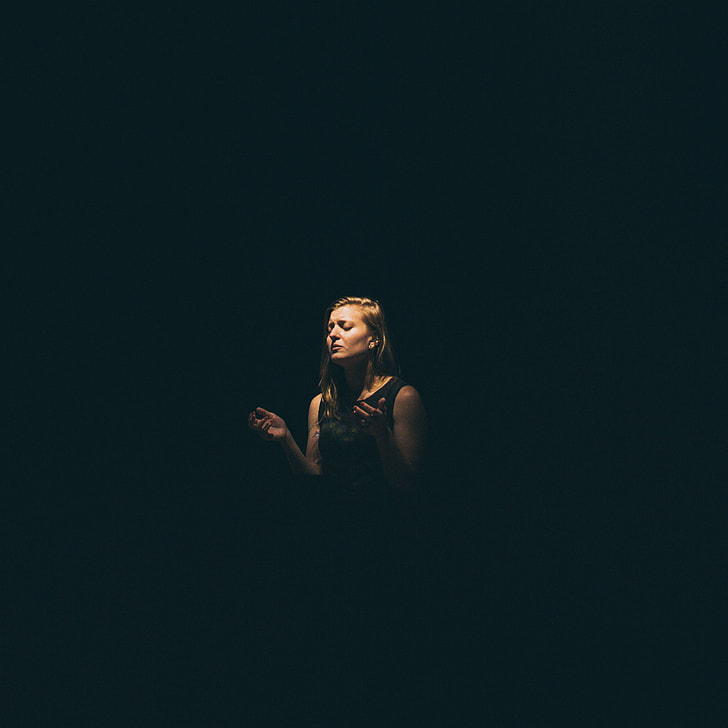 woman in black tank top raising hand in dark