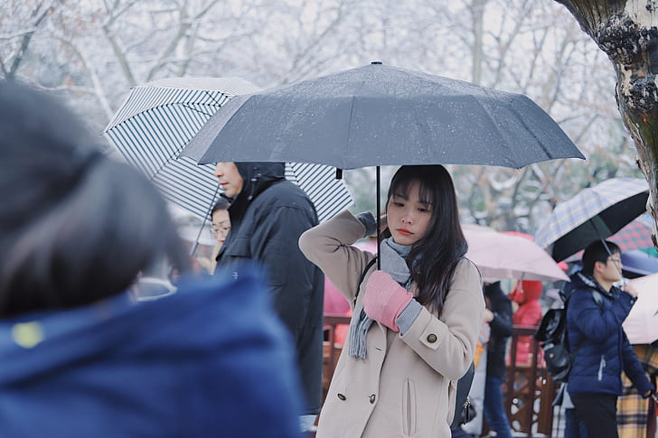 woman wears gray coat holds umbrella