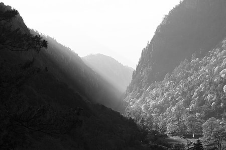 grayscale photography of mountains under sunny sky