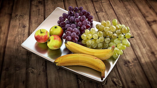 three green-and-red apples, two ride bananas and green-and-purple grapes on rectangular white ceramic plate