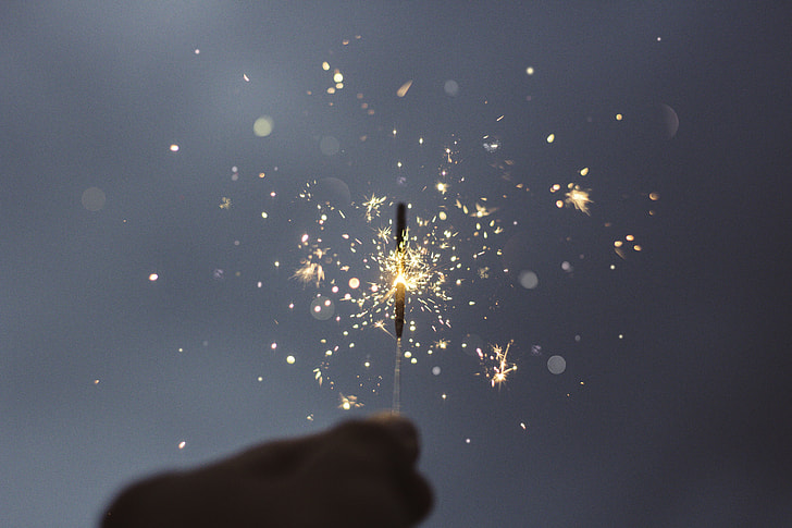 person holding sparkle firecracker in auto focus photography