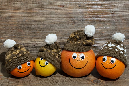 three orange fruits and one yellow citrus with bobble caps