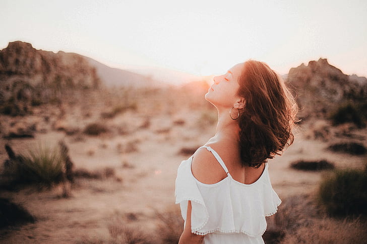 woman wearing white cold-shoulder shirt standing on desert during golden hour time
