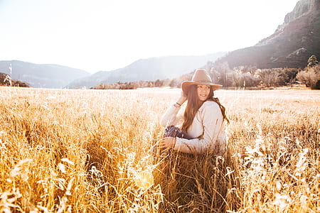 Woman Sitting on Grass Wearing Sun hat Field