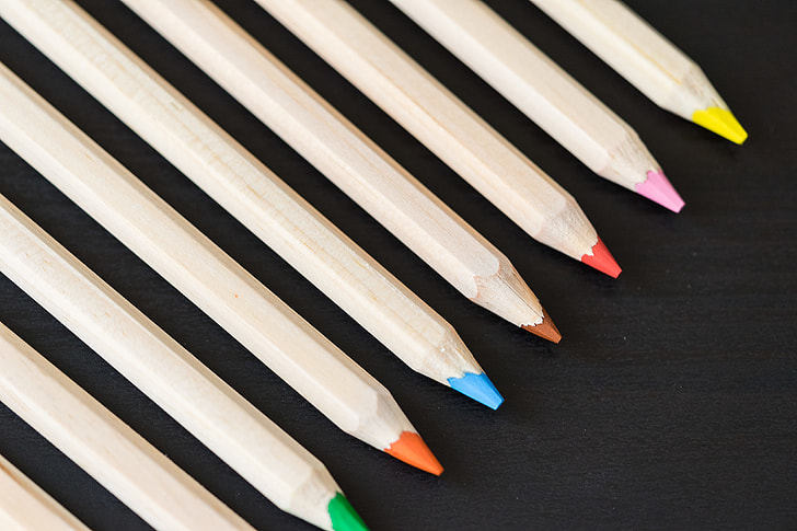 Long Colored Pencils in a Row on Black Desk