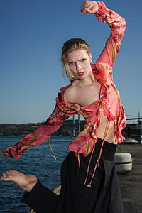 photo of woman in floral top in body bending near body of water