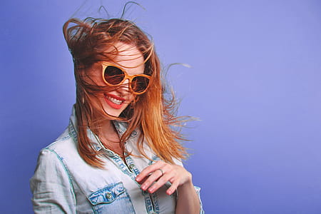 woman wearing gray denim button-up jacket and orange framed sunglasses
