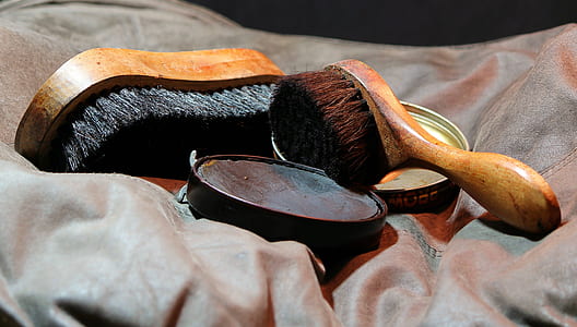 two brown handle shoe brushes on grey textile