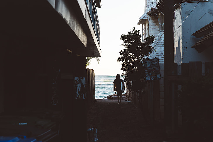 woman walking in between houses near sea shore