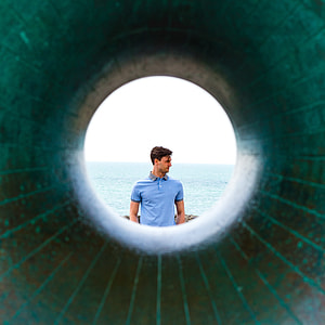 man in blue polo shirt standing distance with ocean during daytime