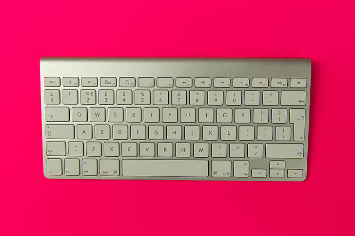 Apple wireless keyboard on pink background
