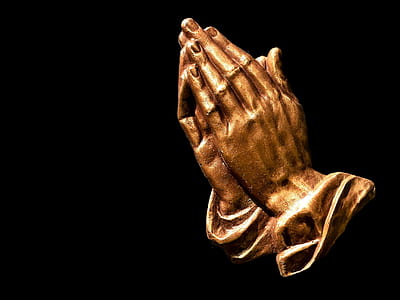 closeup photo of brass-colored praying hands figurine
