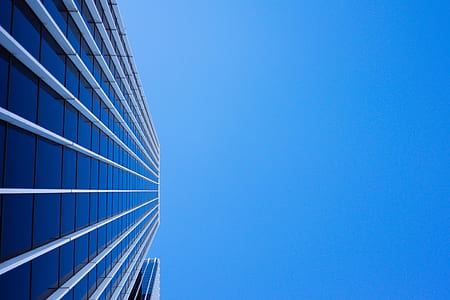 low-angle photo of curtain wall high-rise building under blue clear sky at daytime