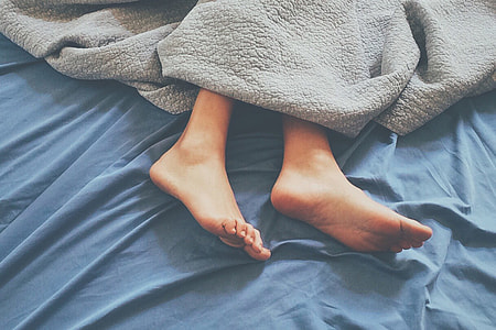 Feet of person sleeping in house home bed