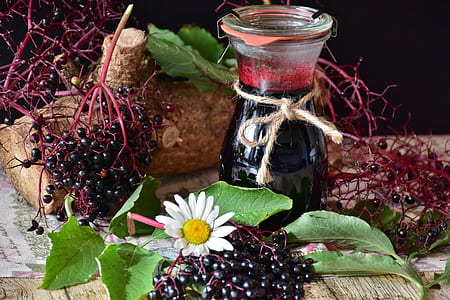 black and red fruit near glass bottle on top of brown wooden surface