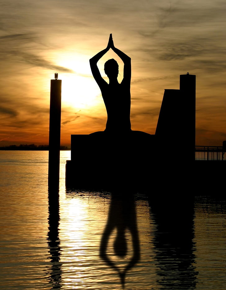 silhouette of person standing on body of water with dance gesture during golden hour
