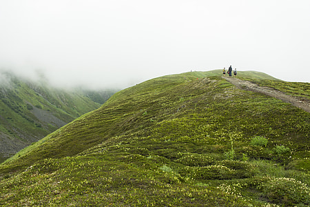 three person on top of mountain surrounded by fog during daytime