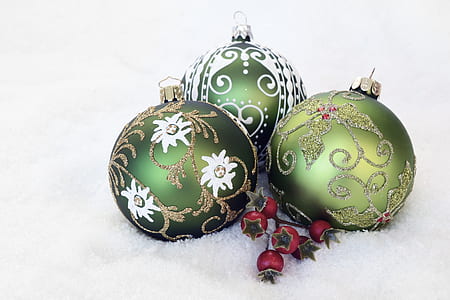 three green Christmas baubles on white surface