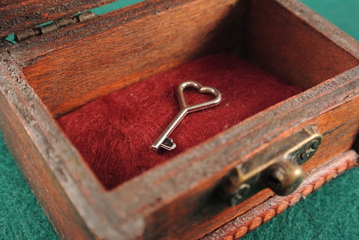 silver heart key on brown wooden chest