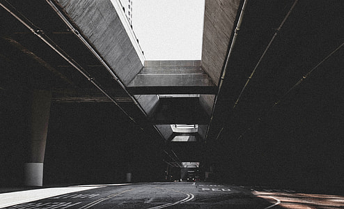 grayscale photo of empty concrete road with concrete long bridge
