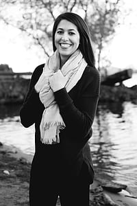Grayscale Photography of a Woman Wearing Sweatshirt and Black Pants While Holding Scarf