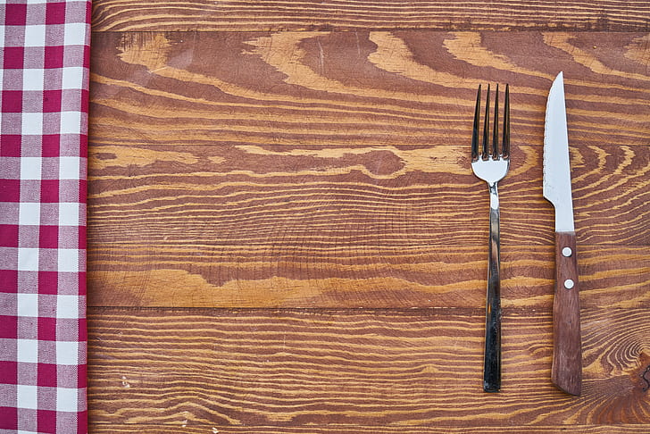 stainless steel fork and knife on brown wooden surface