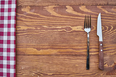 stainless steel fork and knife on brown wooden surface