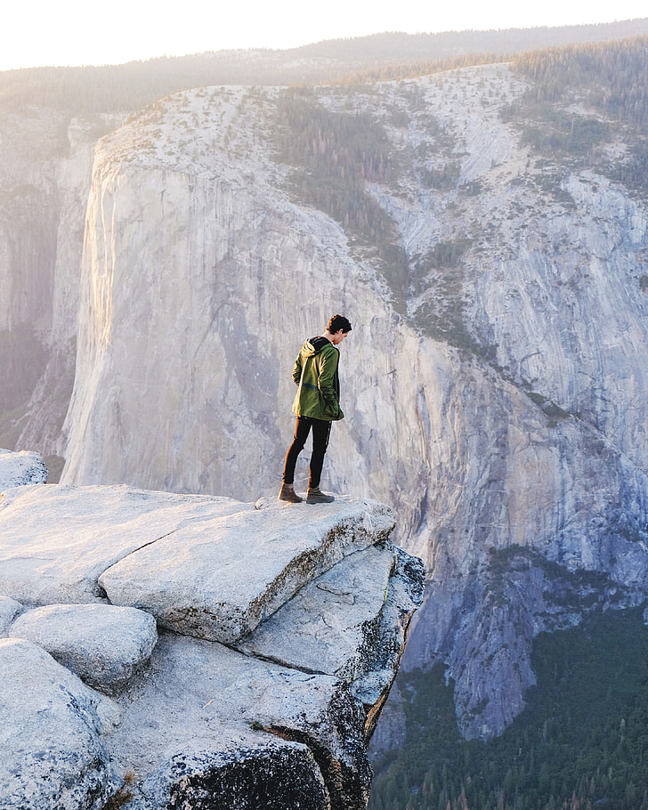 man standing on cliff on rock