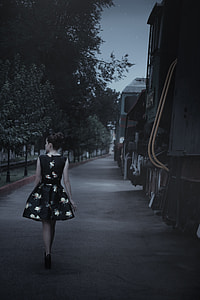 woman wearing black and white floral circle dress walking beside houses