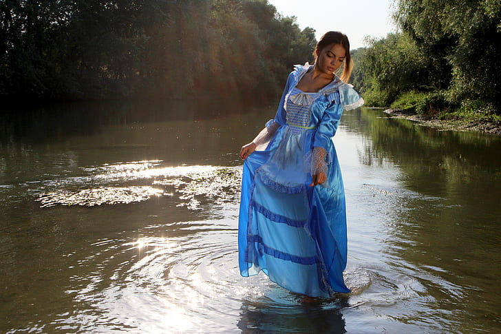 woman in blue dress standing on body of water