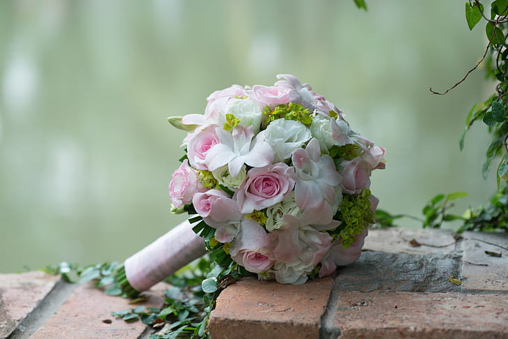 white and pink flower bouquet on brown paver brick