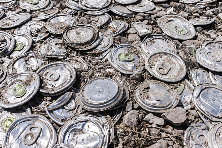 grey flat soda cans with rocks during daytime