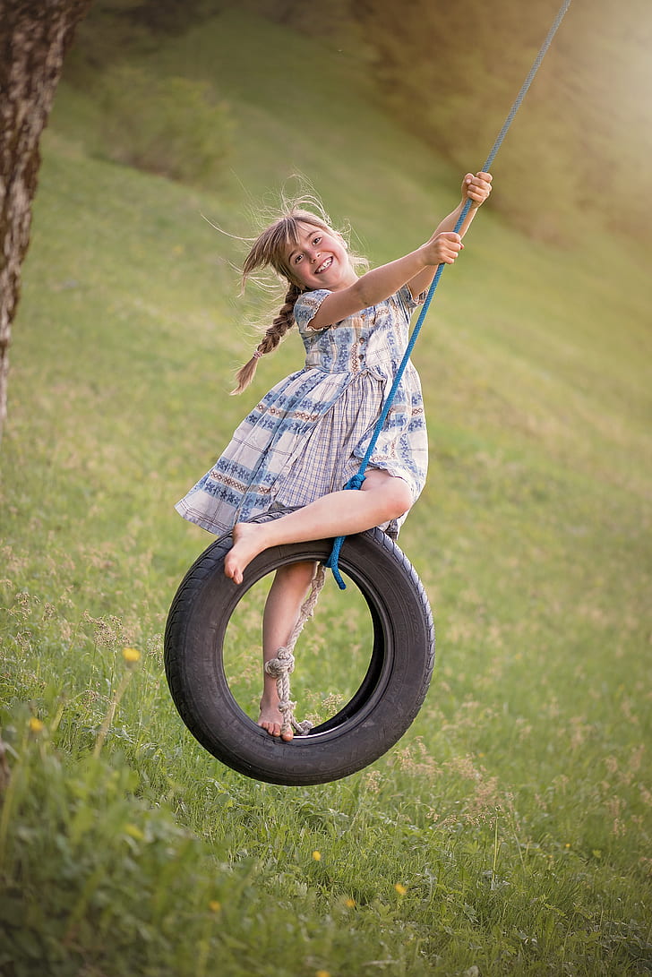 woman wearing blue and gray dress on rubber tire swing