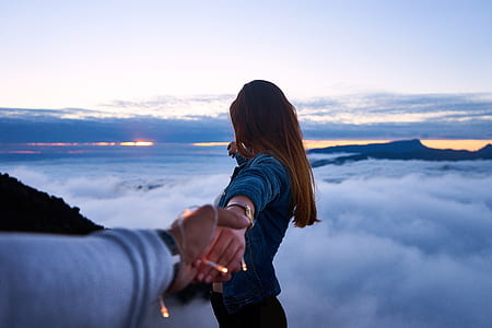 man holding woman's hand on top of mountain