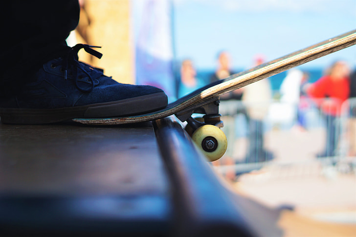 A man’s foot rests on his skateboard