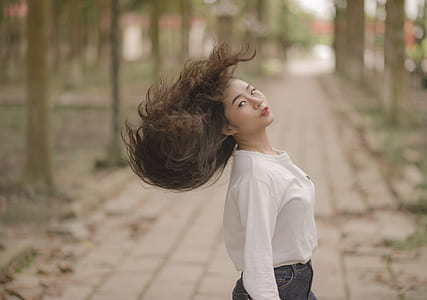Closeup Photo of Woman in White Crew-neck Long-sleeved Shirt Shaking Her Hair in the Middle on Road