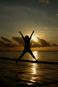 silhouette of person jumping on seashore during sunrise