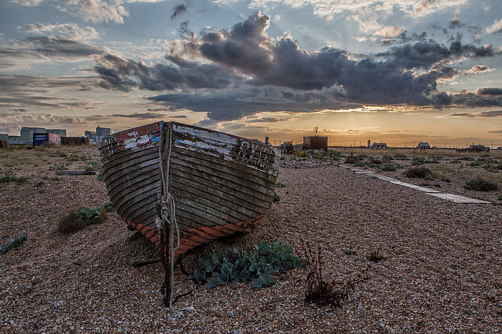 Wide angle landscape shot of an old fishing boat on the beach at sunset in Dungeness in Kent, England. Image captured with a Canon DSLR