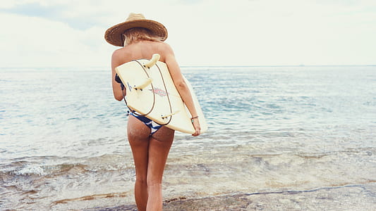woman carrying surfboard walking towards the sea
