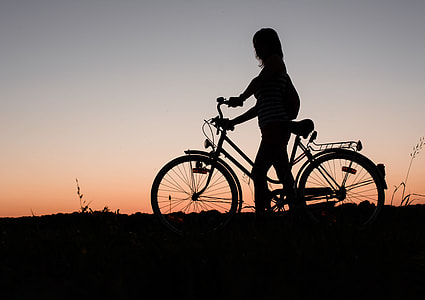 silhouette of woman holding bicycle