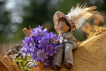 photo of purple flowers beside gray doll during daytime